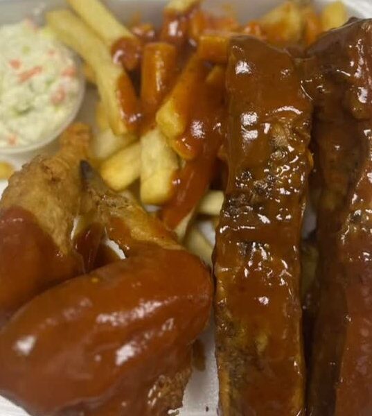 Rib tips and wings in barbecue sauce over fries with coleslaw