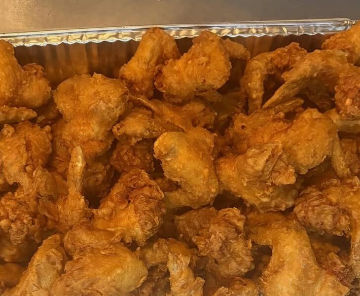 A catering tray piled with golden fried wings